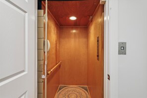 An elevator with wooden walls, a handrail, and a patterned mat at the bottom. - Coastal Bliss Nestled in Bethany Beach: Oceanside, Elevator, Sleeps 16 (South Bethany)
