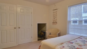 A bedroom with a bed, a chair, a door, and a window with blinds. - Spacious Bayside 5 Bedroom in Bethany Beach! (South Bethany)
