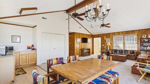A dining area with a wooden table and colorful upholstered chairs, a ceiling fan, and a chandelier. - Bayside South Bethany Home (South Bethany)