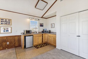 A compact kitchen with wooden cabinets, a built-in microwave, a toaster, and a dishwasher. - Bayside South Bethany Home (South Bethany)