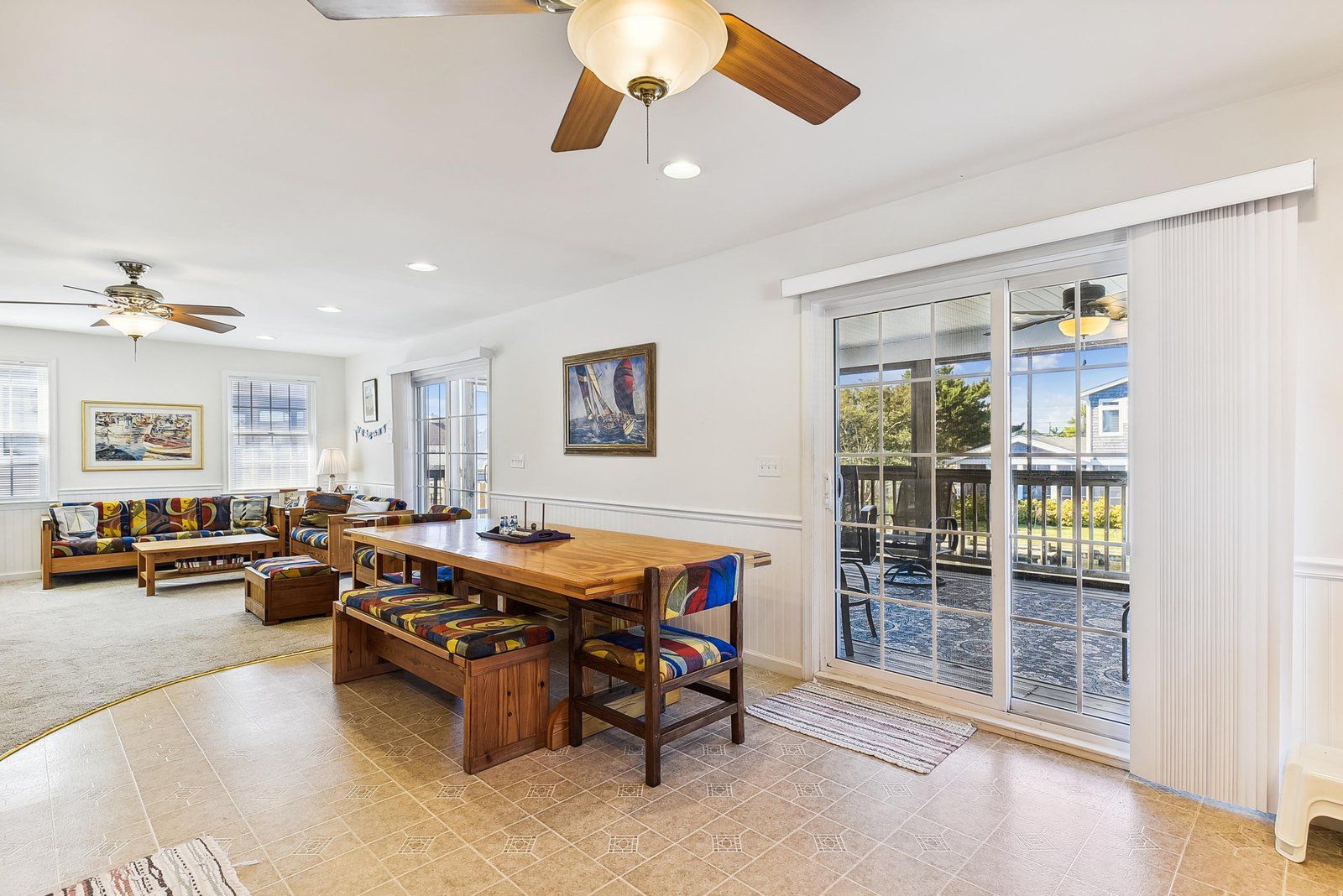 A spacious living room with a wooden dining table, comfortable seating, and a large sliding glass door leading to an outdoor patio.