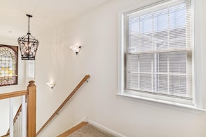 A staircase with a wooden handrail, a stained glass window, and a wall-mounted light fixture.