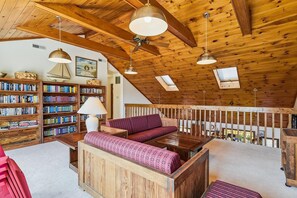 A cozy reading nook with a wooden bench, bookshelves, and a skylight. - Bethany Beach Coastal Retreat (South Bethany)