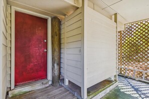 A wooden door with a metal handle, a wooden post, and a white exterior wall.