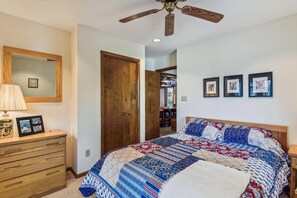 Un dormitorio con cama de madera, cómoda, espejo y ventilador de techo.