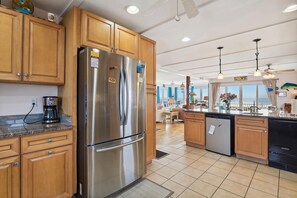 A modern kitchen with wooden cabinets, stainless steel appliances, and a view of the ocean. - The Buffer Zone: Oceanfront Bliss in Bethany Beach (South Bethany)