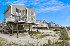 A beachfront house with a balcony, wooden deck, and a sandy beach in the background. - The Buffer Zone: Oceanfront Bliss in Bethany Beach (South Bethany)