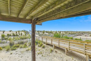 A wooden deck with a view of a sandy landscape and sparse vegetation. - The Buffer Zone: Oceanfront Bliss in Bethany Beach (South Bethany)