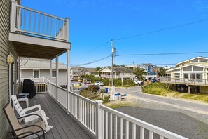 A coastal residential area with a wooden deck, a covered porch, and a view of neighboring houses. - The Buffer Zone: Oceanfront Bliss in Bethany Beach (South Bethany)
