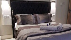 Ein modernes Schlafzimmer mit einem großen Bett, einem dunklen Kopfteil und zwei Nachttischlampen.
