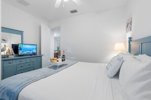 Et soveværelse med seng, fjernsyn, kommode og lampe.