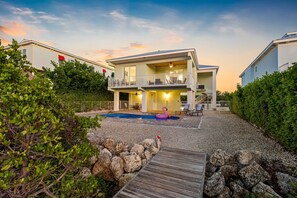 Et toetagers hus med balkon, swimmingpool og træterrasse.