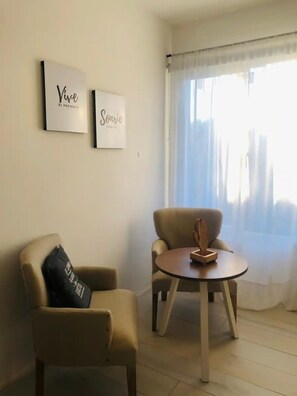 Relax in this serene living room with two armchairs, a small table, and framed art pieces.
