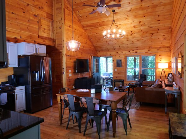 Interior de una cabaña de madera con cocina, comedor y sala de estar.