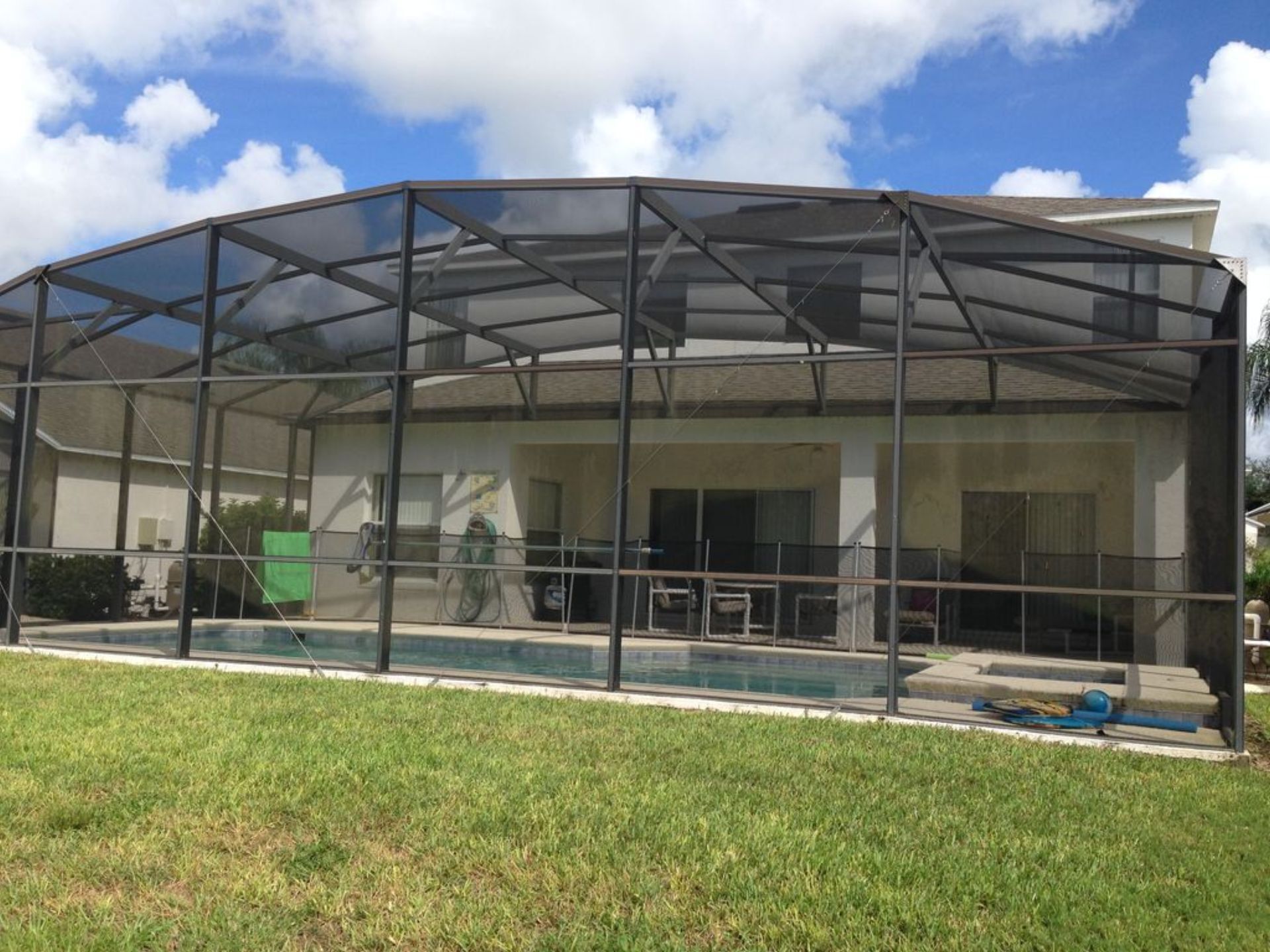 Un área exterior techada con piscina, rodeada por una estructura de metal.