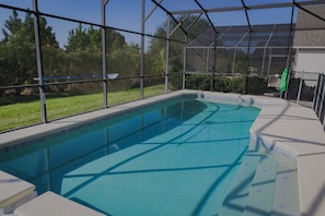 Una piscina interior con paredes de vidrio transparente, rodeada por un patio cubierto.