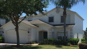 A two-story house with a garage, a front porch, and a well-maintained lawn.