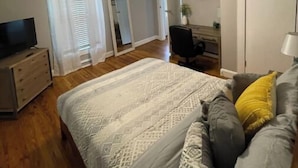 A bedroom with a bed, a desk, a chair, a television, and a ceiling fan. - Historic Mill House
 (Lexington)