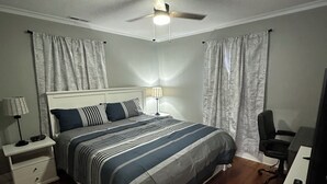A bedroom with a bed, nightstand, desk, chair, and curtains. - City Cottage Winston-Salem
 (Winston-Salem)