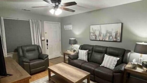 A living room with a leather sofa, a wooden coffee table, a ceiling fan, and a painting on the wall. - Uptown Thomasville (Thomasville)