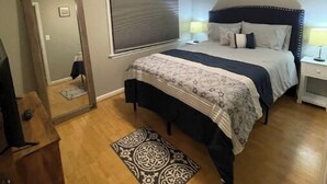 A bedroom with a bed, a ceiling fan, a mirror, and a wooden dresser. - Uptown Thomasville (Thomasville)