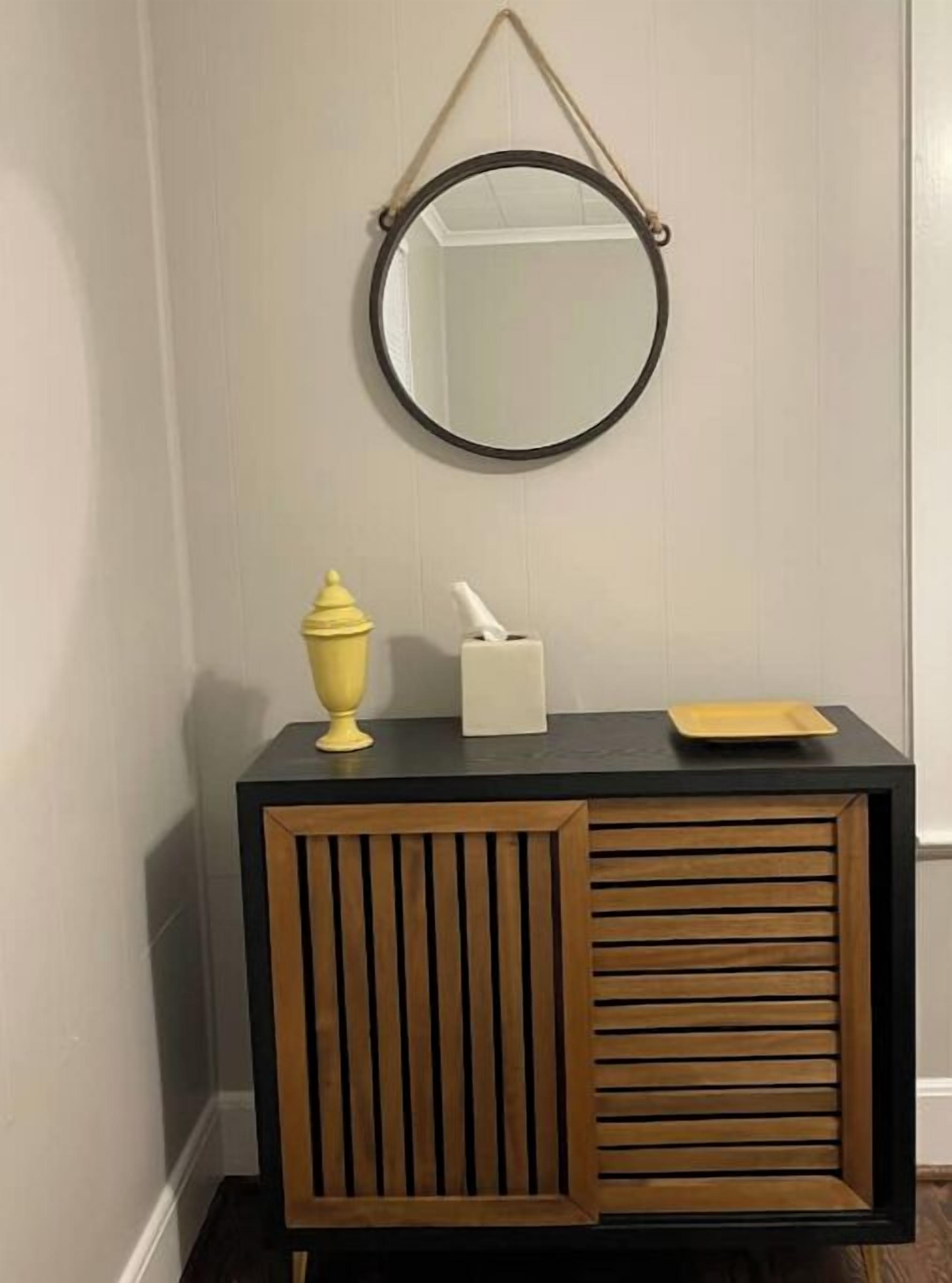 Una consola de madera negra con un espejo encima, un florero amarillo, una caja de pañuelos y una bandeja amarilla.