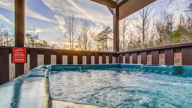 Ein Whirlpool unter einer Holzw pergola mit Blick auf Bäume und einen klaren Himmel.