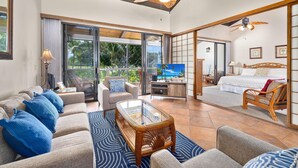 A spacious living area with a sofa, coffee table, and a television. There is a balcony with a view of the outdoors. - Keauhou Kona Surf & Racquet Club#6-303 (Kailua-Kona)