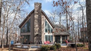 Una casa moderna con chimenea de piedra, ventanas amplias y una terraza con mobiliario exterior.