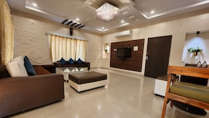 A modern living room with a sofa, ottoman, and a coffee table. - Teakwood Farms (Wardha)