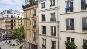 Un edificio de varios pisos con balcones, ventanas amplias y una calle empedrada.