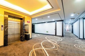 A hotel corridor with a marble elevator, a trash bin, and a patterned carpet. - Hongsheng Business Hotel (Nanchang)