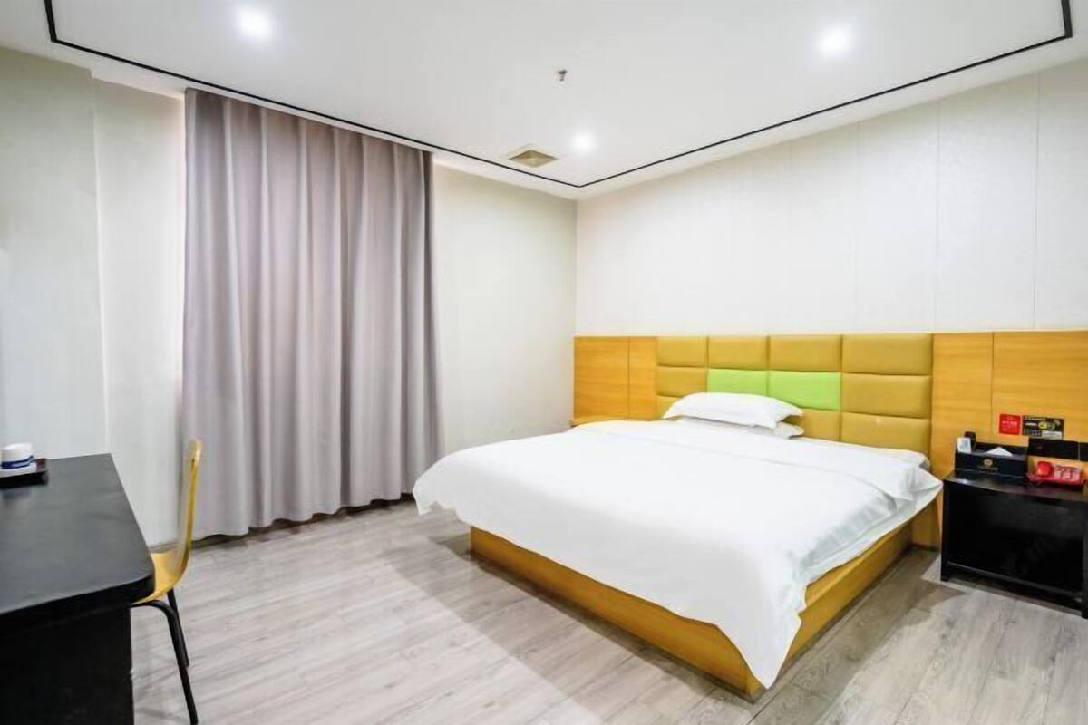 Une chambre d’hôtel avec un lit, un bureau, une chaise et une table de chevet.