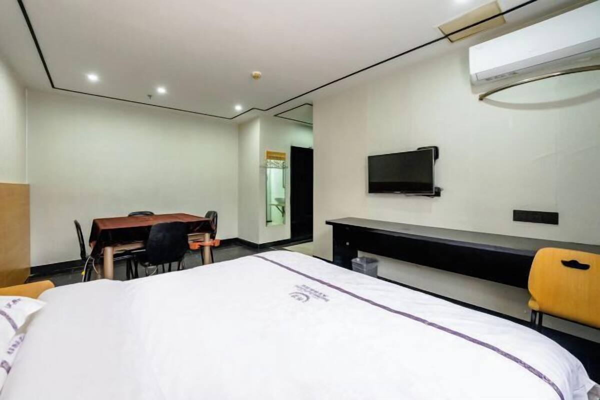 Une chambre d’hôtel équipée d’un lit, d’un bureau, d’une chaise, d’une télévision et d’un appareil de climatisation.