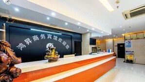 A hotel reception area with a black and orange color scheme, a reception desk, and a decorative sculpture. - Hongsheng Business Hotel (Nanchang)