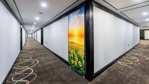 A hallway with a long corridor, a large wall mural of a sunset over a sunflower field, and a patterned carpet. - Hongsheng Business Hotel (Nanchang)