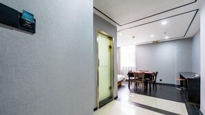 A hotel room with a bed, a desk, and a chair. There is a door leading to another room. - Hongsheng Business Hotel (Nanchang)