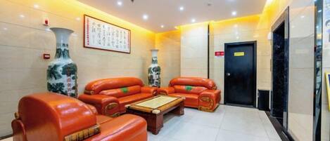 A lobby with leather sofas, a coffee table, and a large vase.