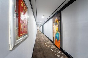 A corridor with framed artwork on the walls, a patterned carpet, and a ceiling with recessed lighting. - Hongsheng Business Hotel (Nanchang)