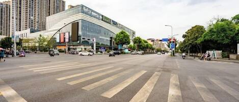 A wide street with a large building, crosswalks, and vehicles.