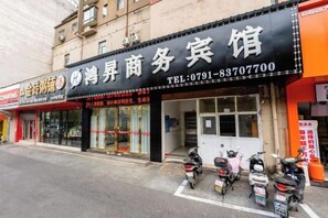 A storefront with a sign for a business, a visible phone number, and several parked scooters. - Hongsheng Business Hotel (Nanchang)