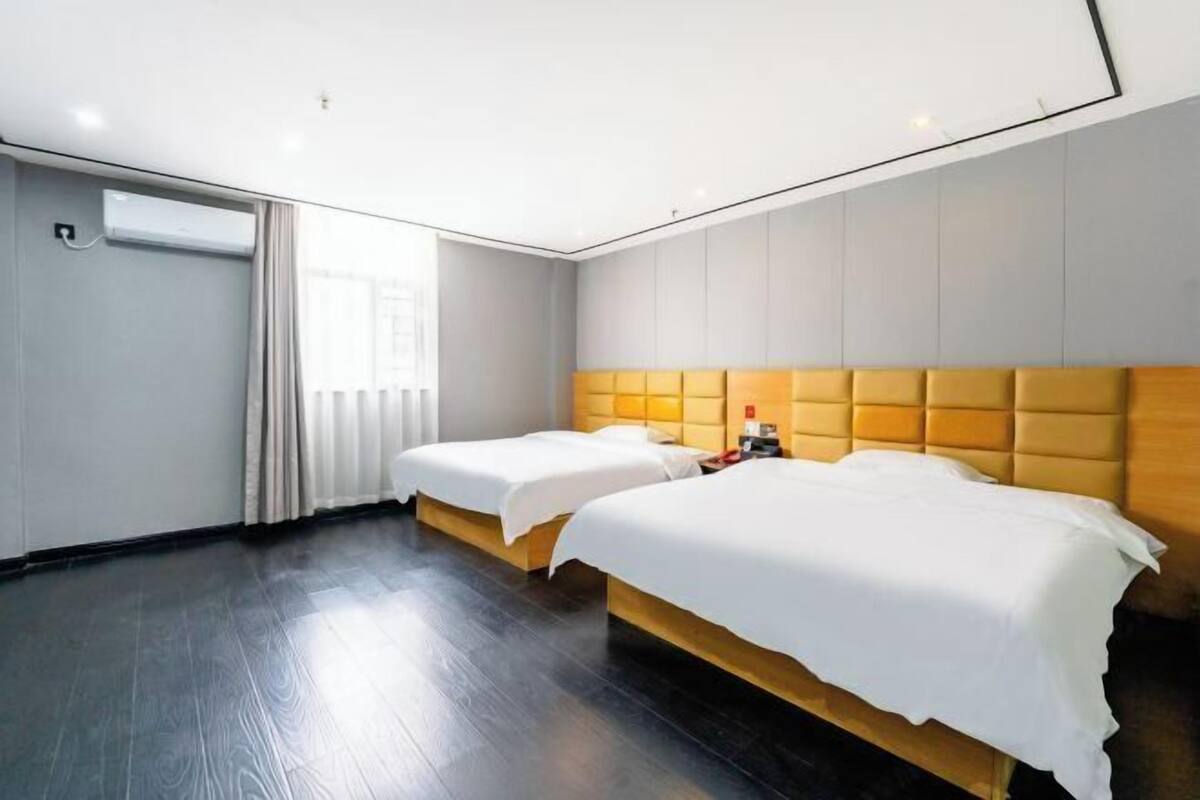 Une chambre d’hôtel avec deux lits, une grande fenêtre et un design moderne.