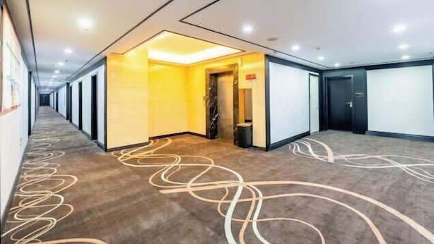A hotel corridor with a modern design, featuring a carpet with abstract patterns, recessed lighting, and a combination of dark and light wall colors. - Hongsheng Business Hotel (Nanchang)