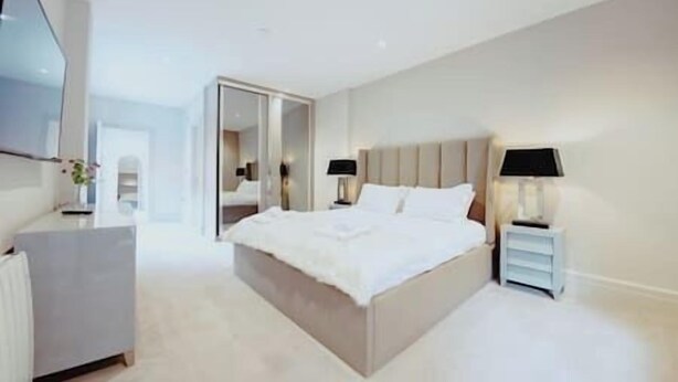 A modern hotel room with a large bed, bedside tables, a flat-screen TV, and a mirror. - The Lodge · 3-Story Townhouse - Sleeps 8
Leeds City Centre  (West Yorkshire)