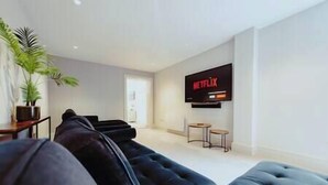A modern living room with a large black sofa, a flat-screen TV mounted on the wall, and a potted plant. - The Lodge · 3-Story Townhouse - Sleeps 8
Leeds City Centre  (West Yorkshire)