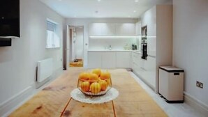 A modern kitchen with white cabinets, a central island with a fruit bowl, and a built-in oven. - The Lodge · 3-Story Townhouse - Sleeps 8
Leeds City Centre  (West Yorkshire)