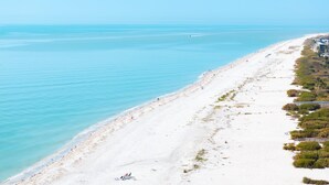 Ein Strand mit freiem Blick auf den Ozean, einem sandigen Ufer und einigen Gebäuden entlang der Küste.