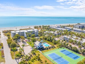 A resort with multiple buildings, a beach, and a tennis court.