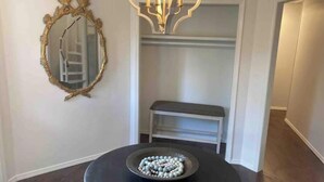 A room with a round black table, a decorative bowl, a gold-framed mirror, and a white bench. - The Castle at Camorene

 (Springfield)