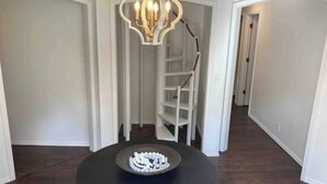 A hallway with a round table in the center, a chandelier, and a staircase. - The Castle at Camorene

 (Springfield)